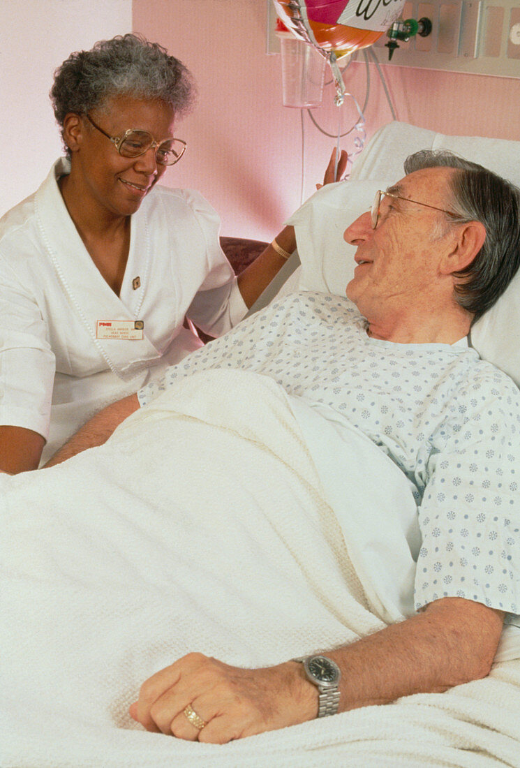 Nurse talking to elderly patient in geriatric ward