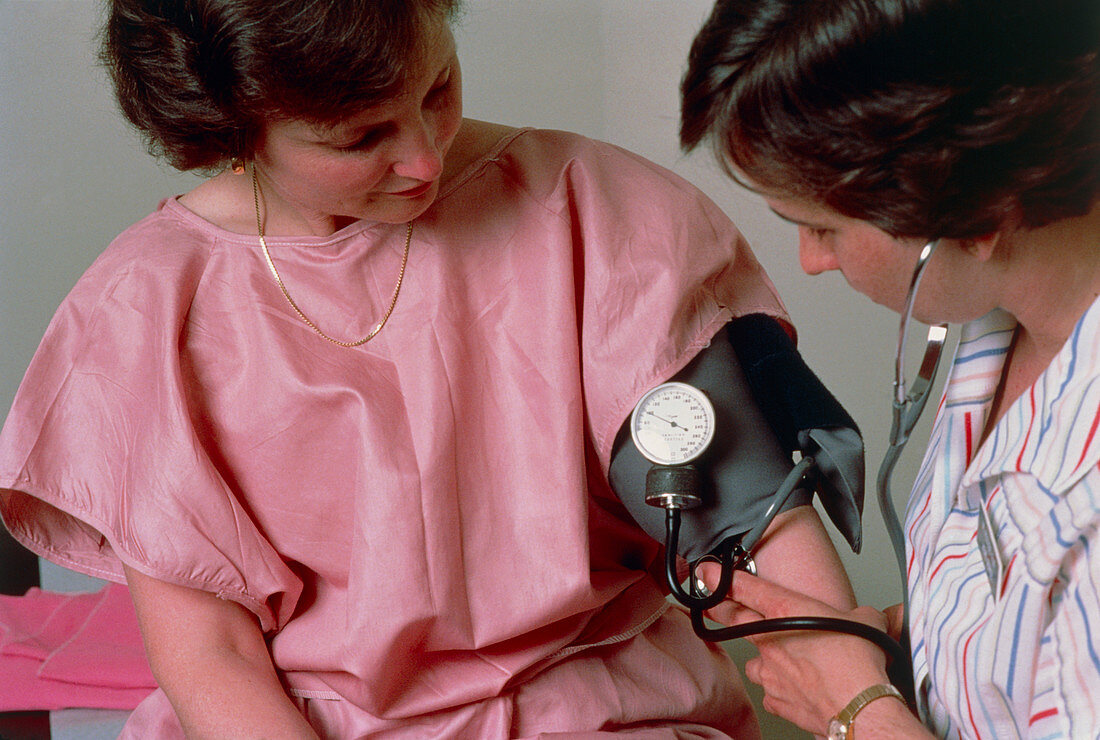 Nurse measuring female patient's blood pressure