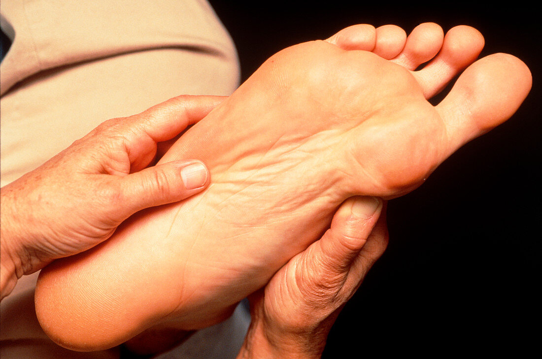 Hands of reflexologist massaging foot