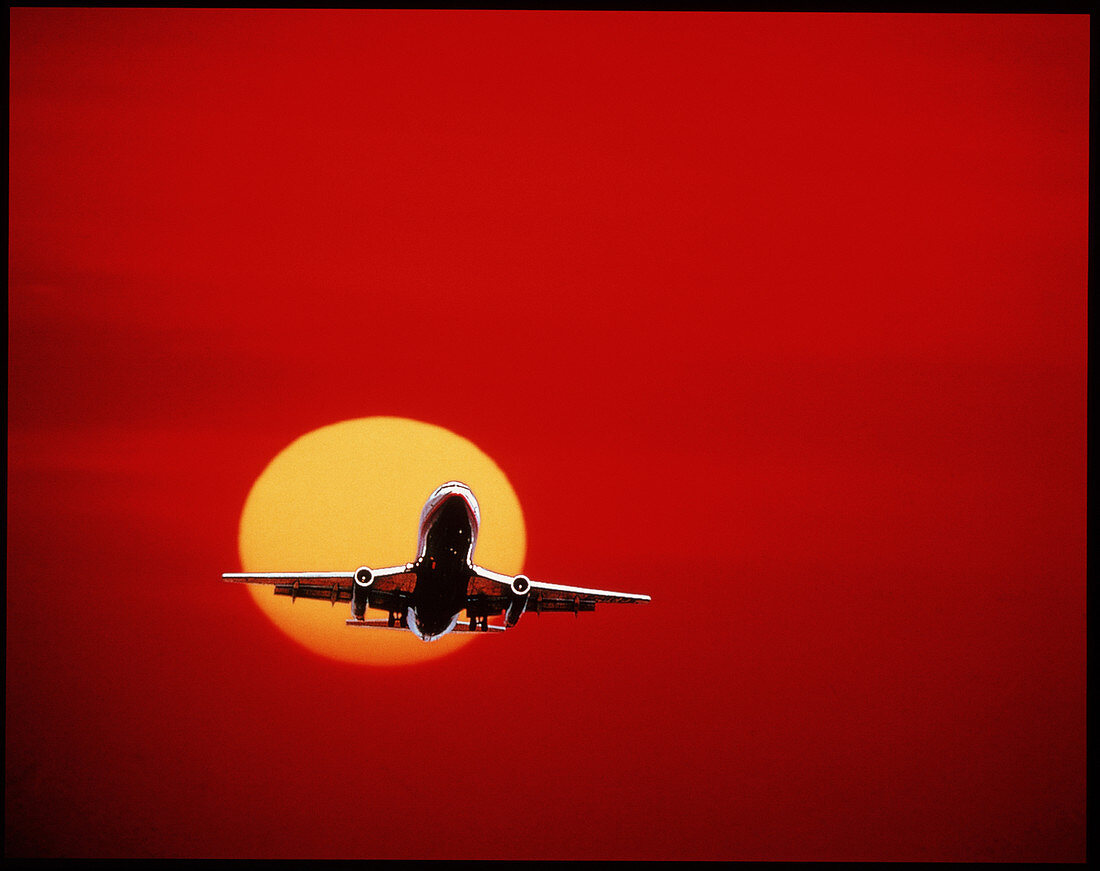 Airliner landing against a setting Sun