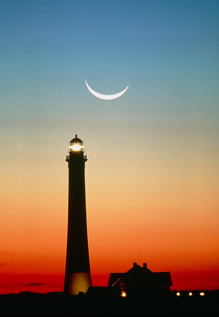 Crescent moon over lighthouse at sunrise