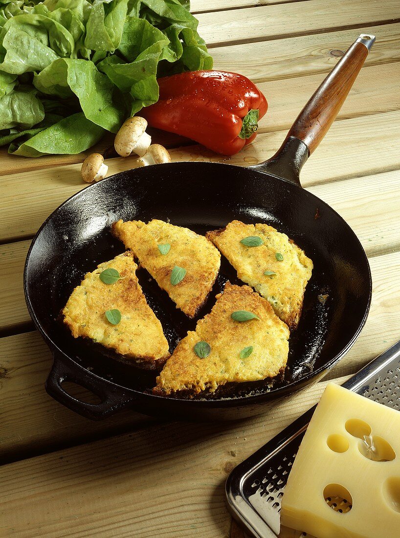 Fried, breaded Allgaeu Cheese Corners with Herbs in Cast-iron Frying Pan