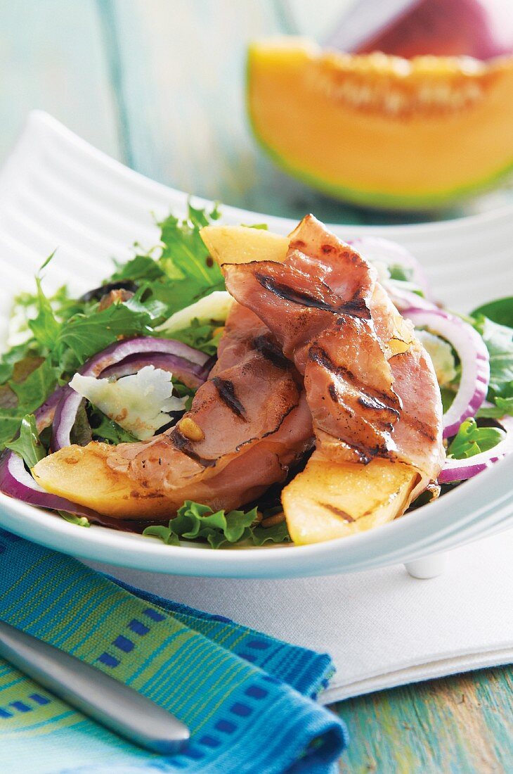 Gegrillte Melonenspalten im Schinkenmantel auf Blattsalat