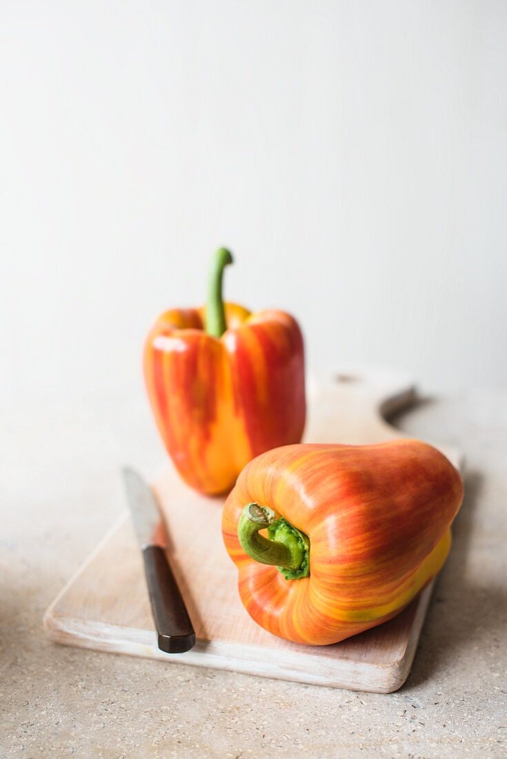 Fresh striped red peppers on a chopping board with a knife