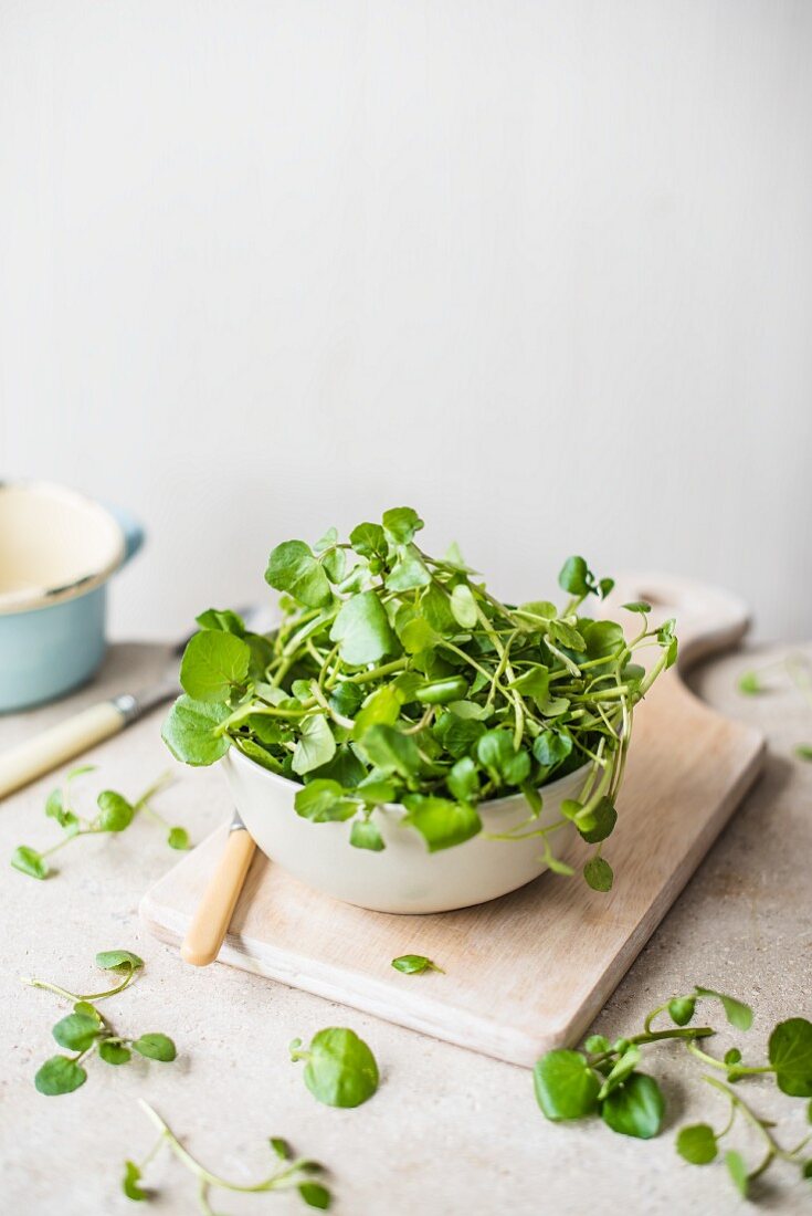 Fresh watercress in a bowl on a chopping board