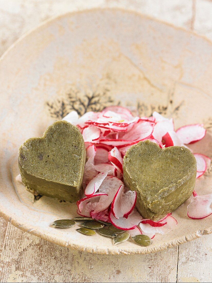 Vegan pumpkin seed and cashew nut cheese hearts with slices of radish