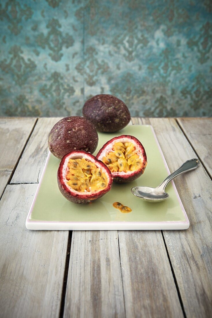 Passion fruit on a chopping board, one sliced in half