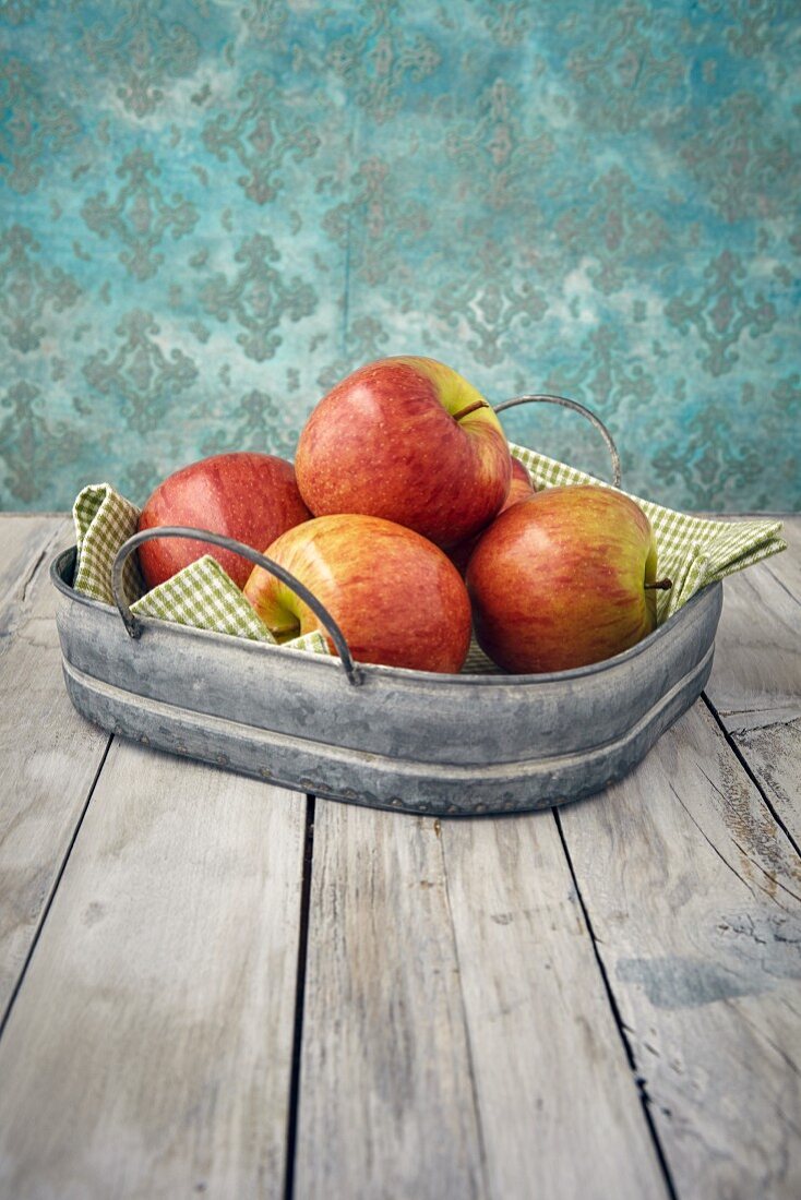 Fresh apples in a metal tray on a wooden table