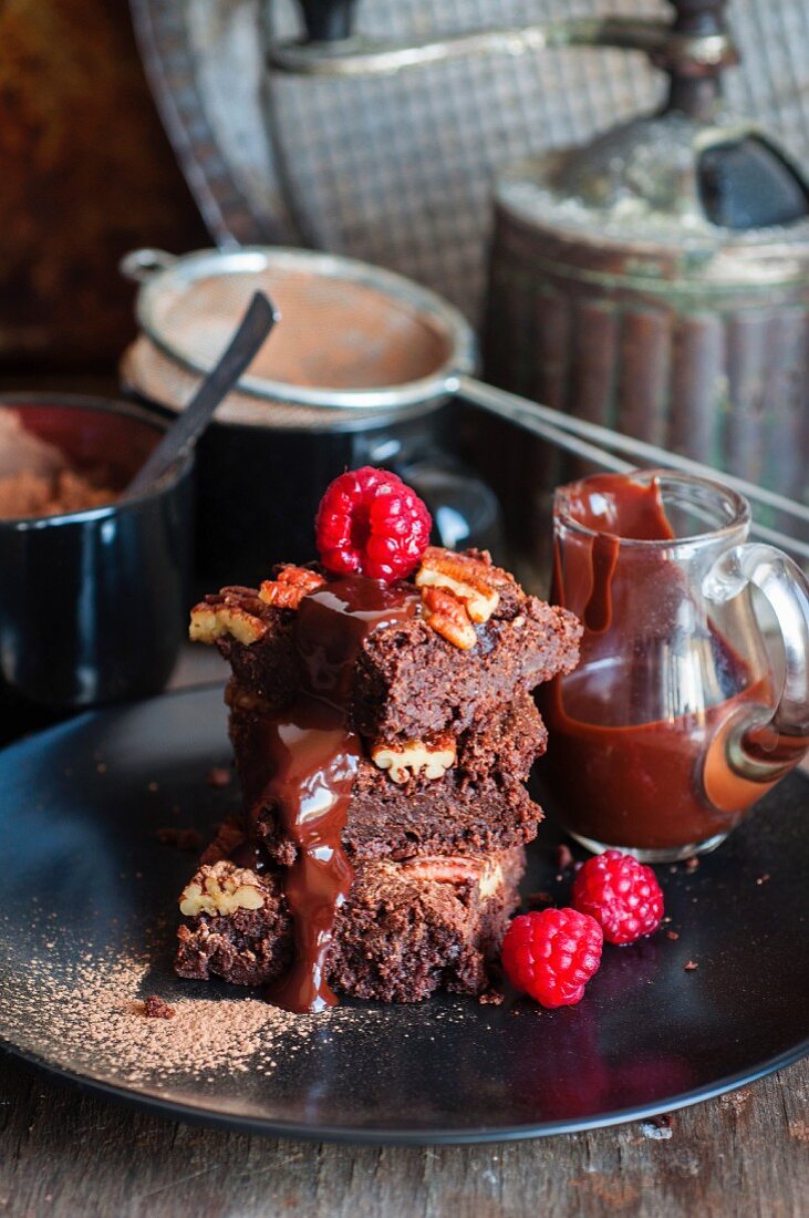 Brownies with pecan nuts, chocolate sauce and raspberries