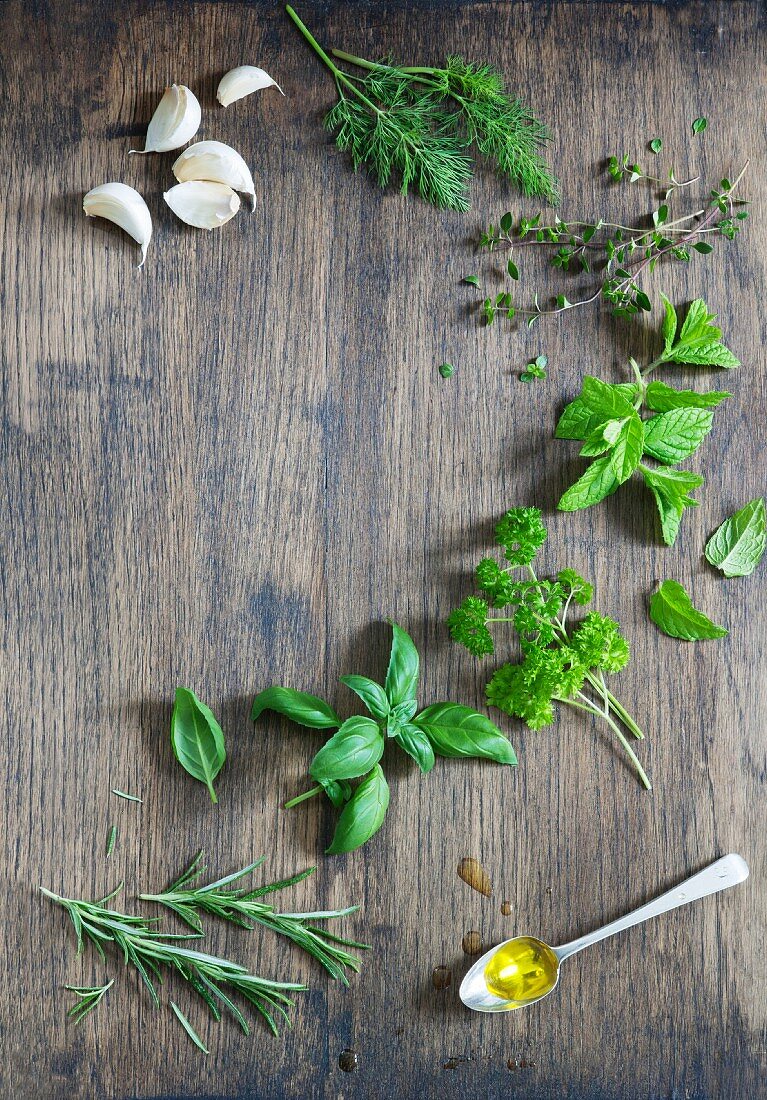 Rosmarin, Basilikum, Petersilie, Minze, Thymian und Dill mit Knoblauchzehen und einem Löffel Olivenöl