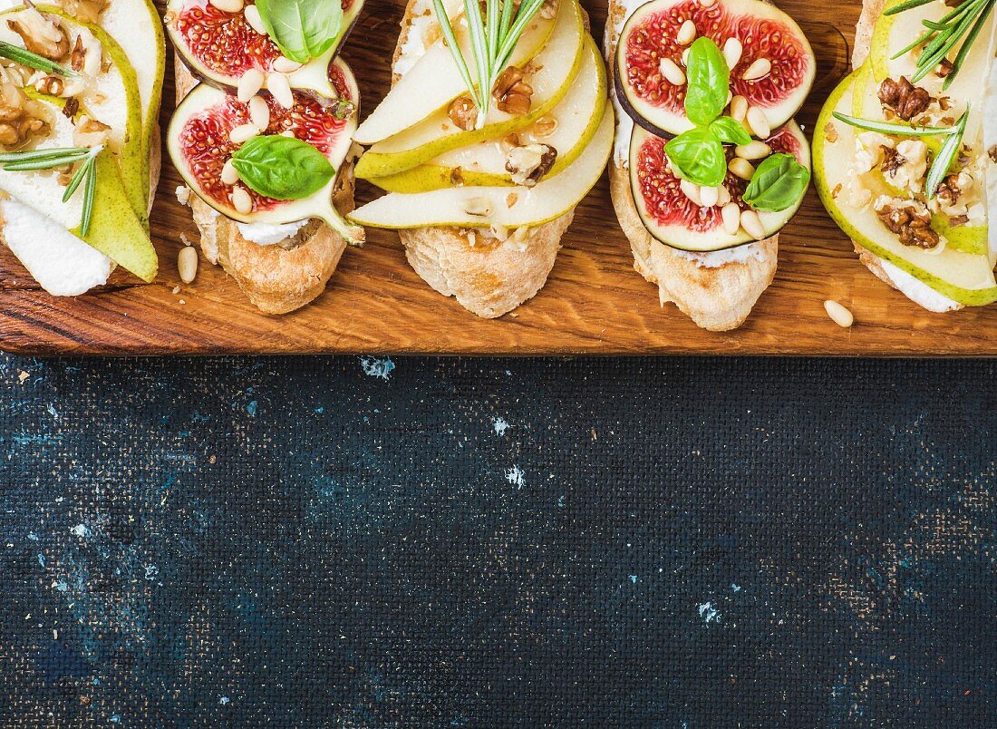 Crostini mit Birnenscheiben, Ricotta, Feigen, Nüssen und frischen Kräutern