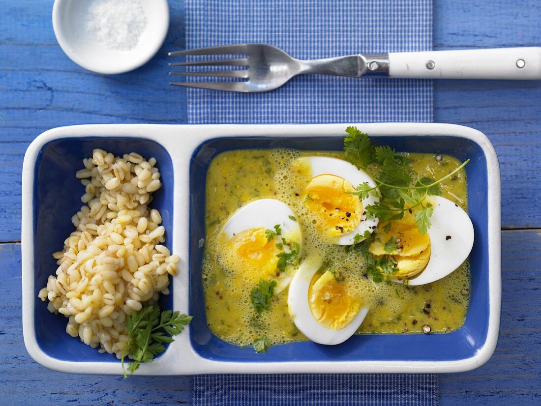 Eggs in curry and mustard sauce with wheat and fresh chervil