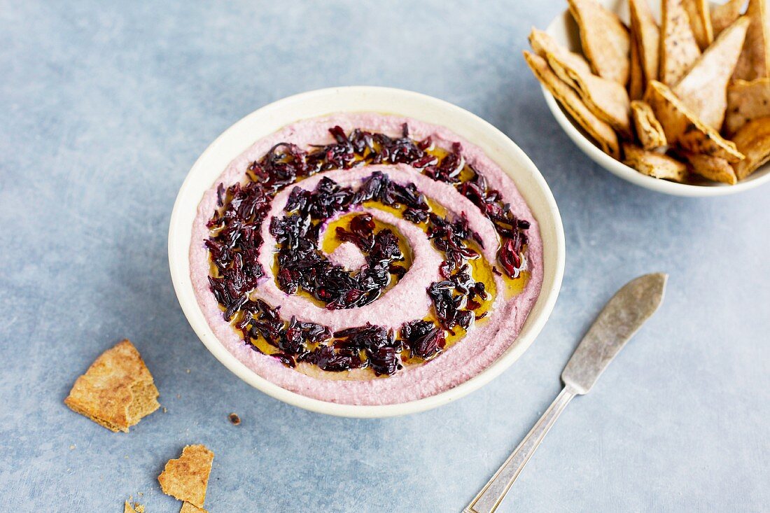 Hibiscus hummus topped with hibiscus flowers and olive oil, served with pita chips
