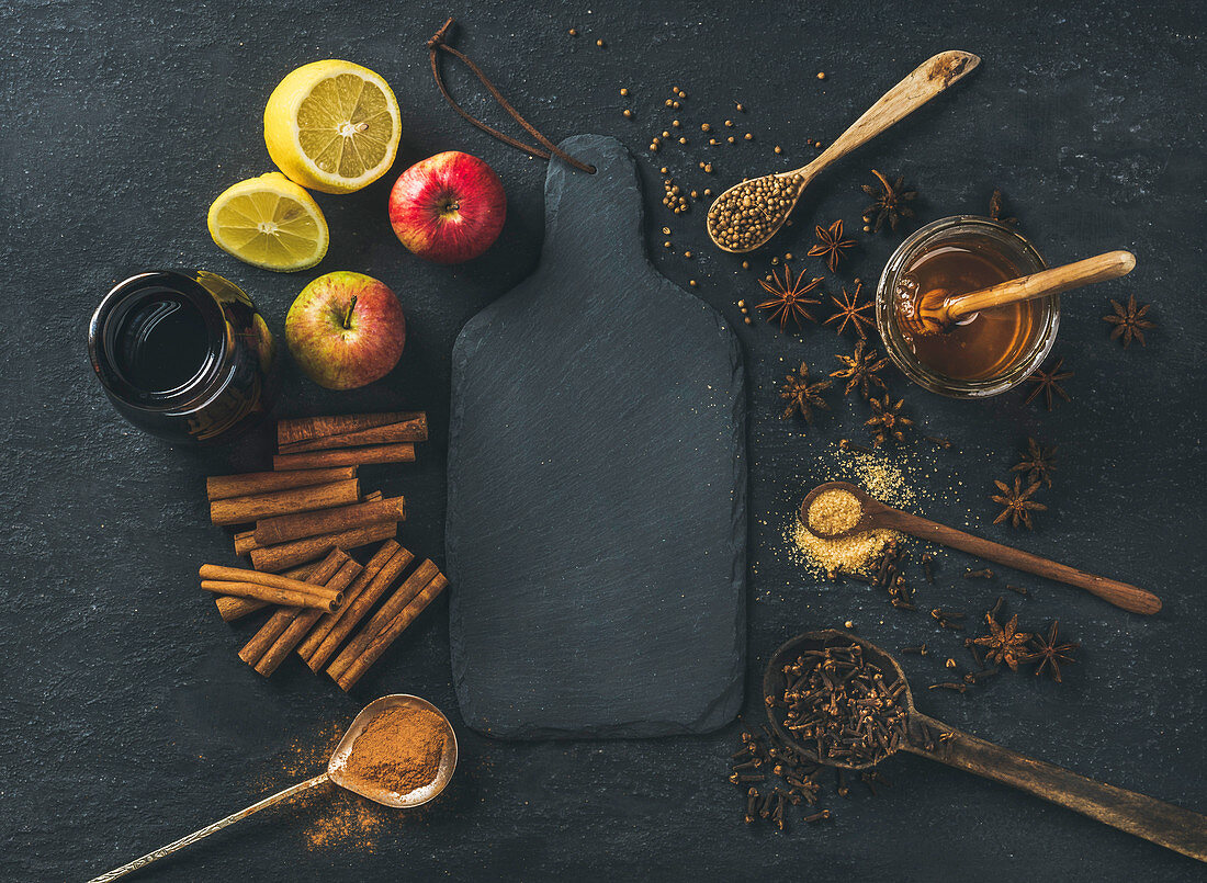 Ingredients for making mulled wine, wine in glass bottle, honey, lemon, apples and spices