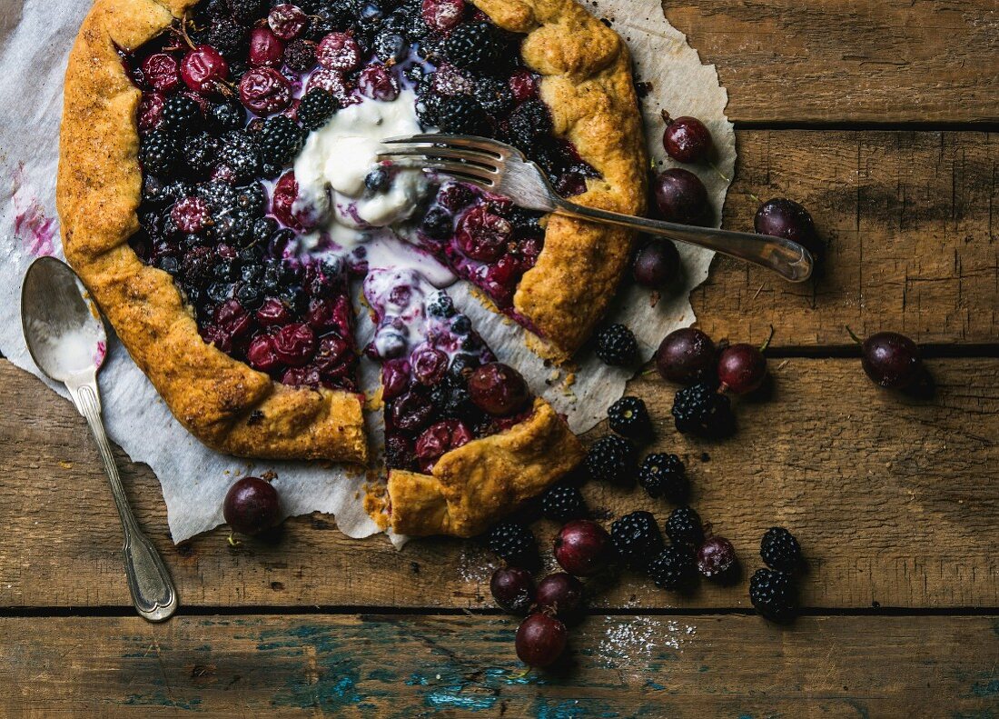 Homemade garden berry galetta or crostata sweet pie with melted vanilla ice-cream