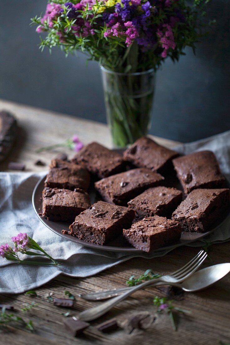 Brownies aus dunkler Schokolade und Kokosöl auf einem Teller auf rustikalen Holztisch