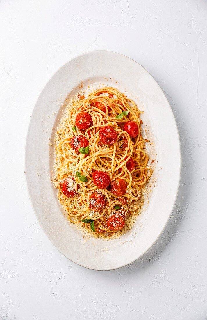 Spaghetti mit Tomatensauce, gebratenen Tomaten und Parmesan auf weißem Hintergrund