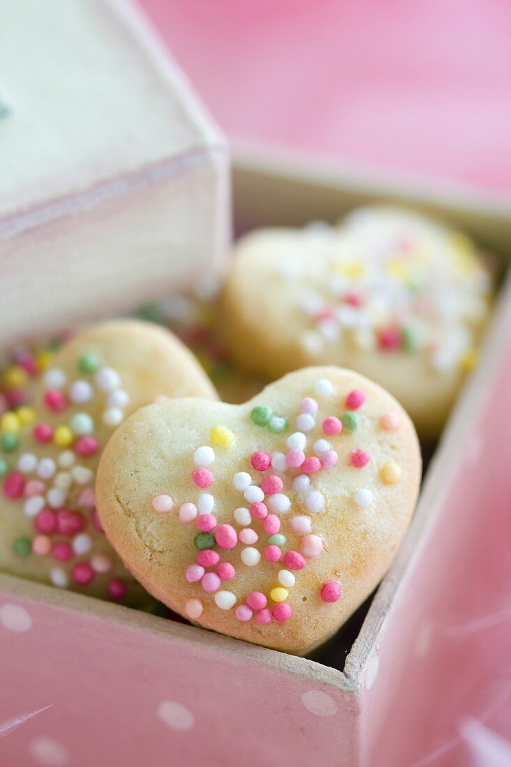 Herzförmige Plätzchen mit bunten Zuckerperlen in einer Geschenkbox