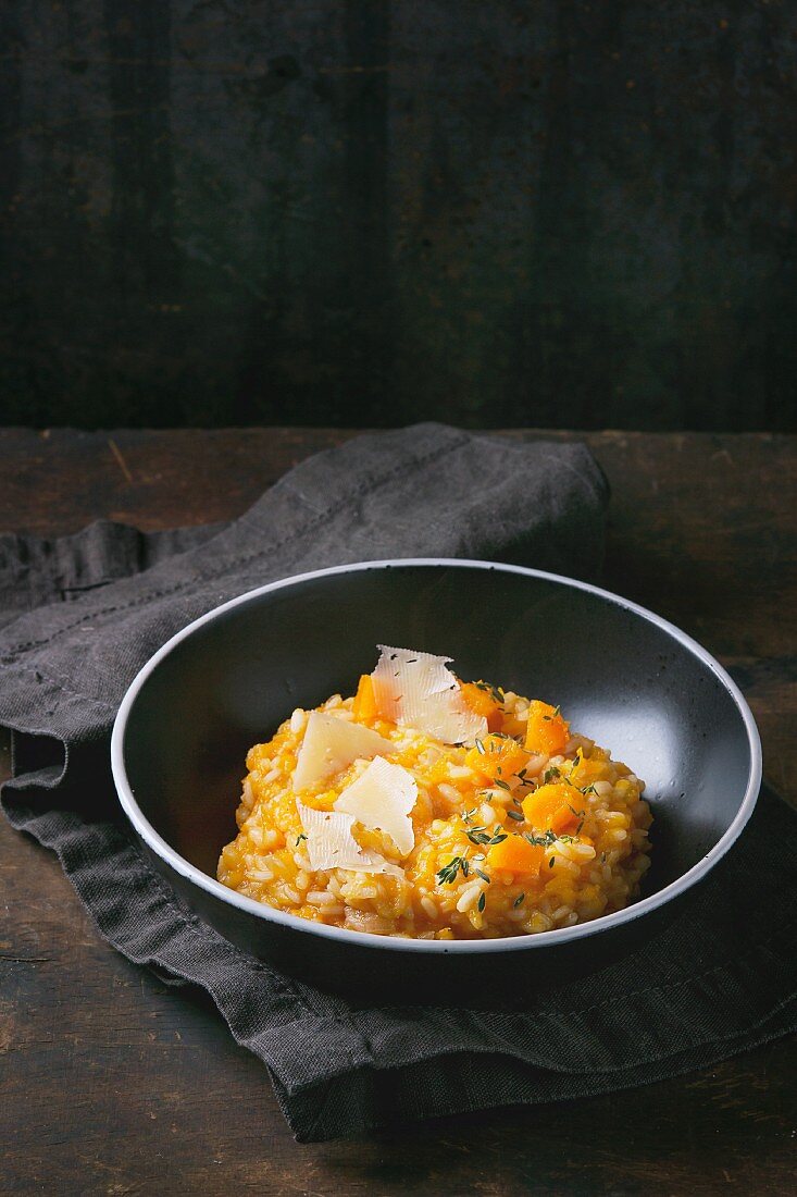 Pumpkin risotto with thyme and cheese on a dark surface