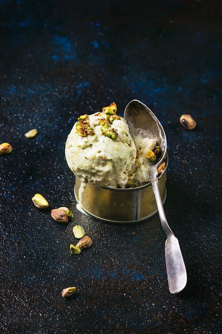 Pistachio ice cream in a tin can with a silver spoon