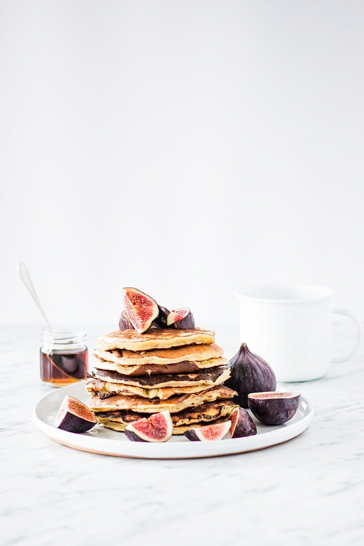 A pile of pancakes with figs and maple syrup