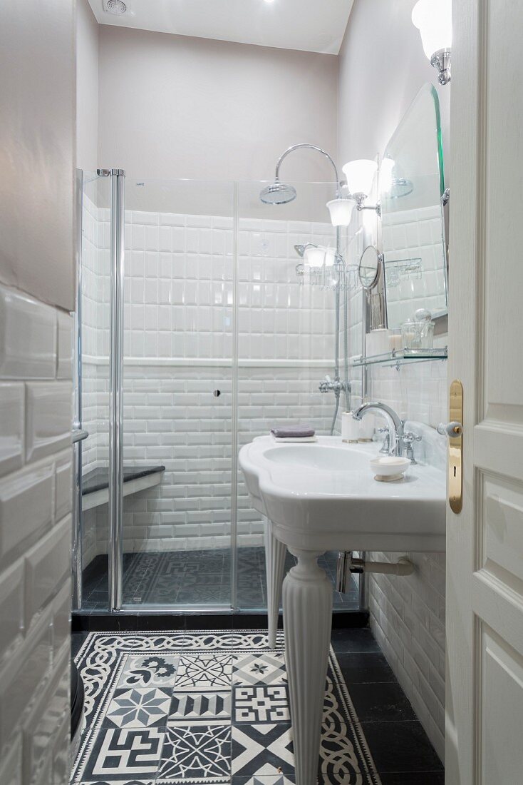 White sink and ornate black and white floor tiles in narrow bathroom