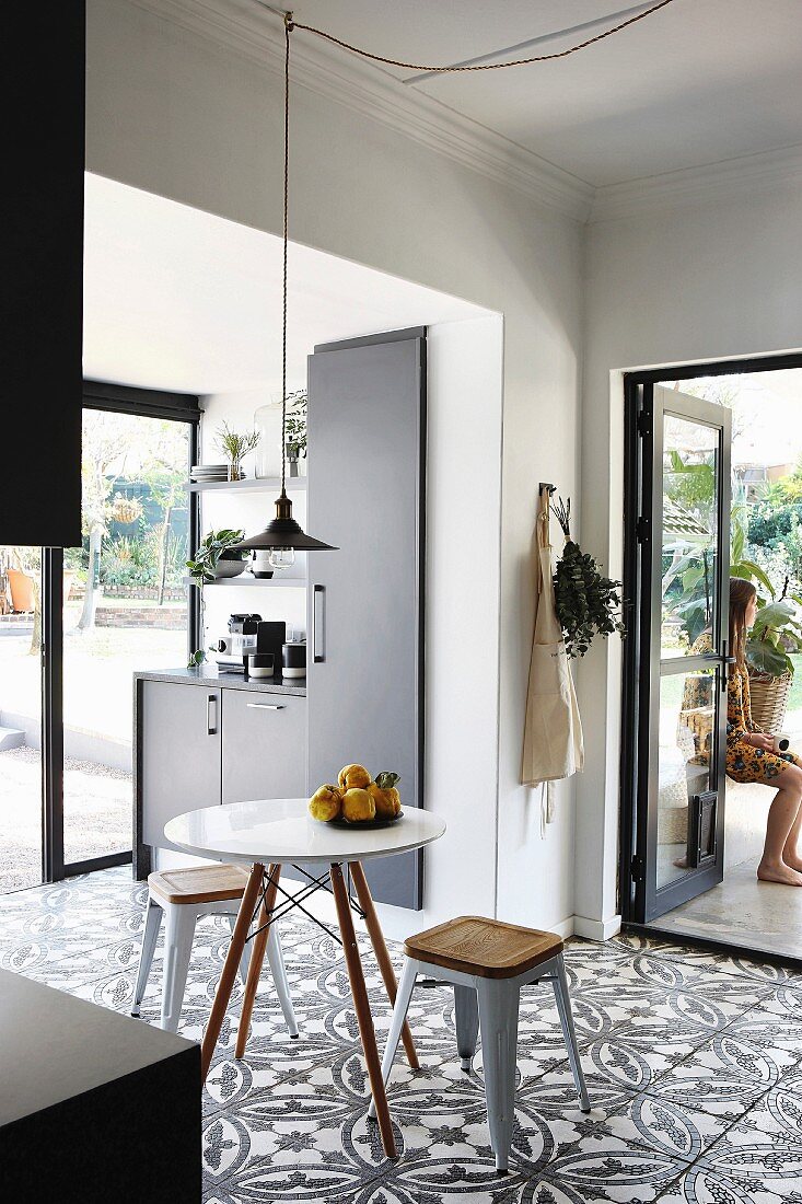 Floral-patterned floor tiles and open terrace doors in black fitted kitchen