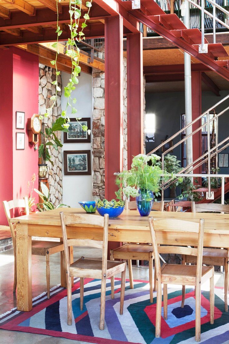 Solid-wood table in dining area of loft apartment with steel staircase in background