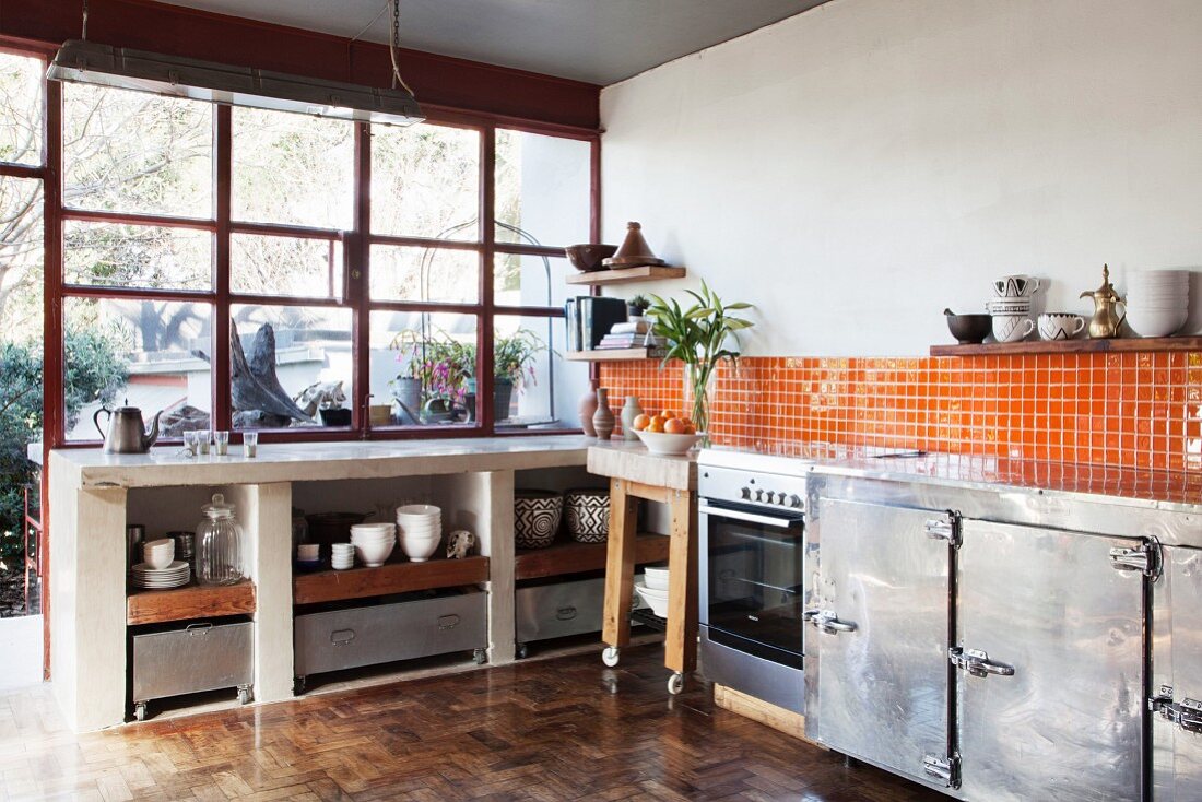 Recycled parquet floor, orange wall tiles and metal cabinets in open-plan kitchen of loft apartment