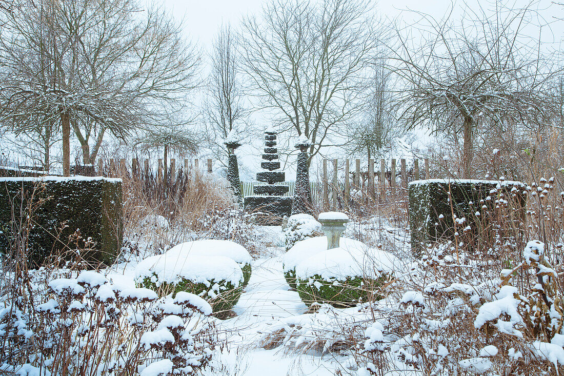 Verschneiter Garten mit Bäumen und Hecken im Winter