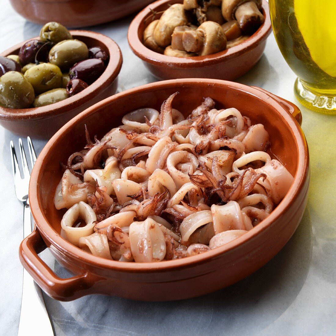 Spanish tapas: pan-fried calamari with olives and mushrooms