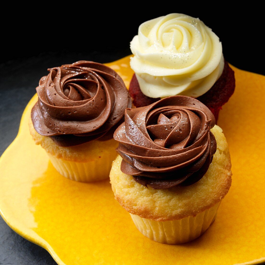 Three cup cakes with dark and white chocolate cream icing