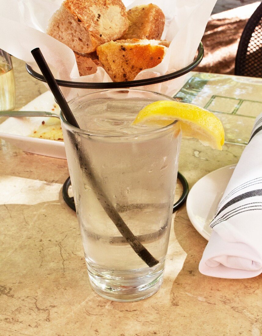 A glass of ice water with a slice of lemon at a restaurant