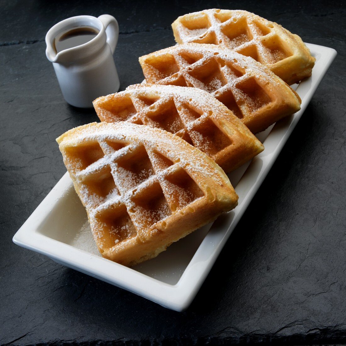 Waffles with icing sugar and syrup
