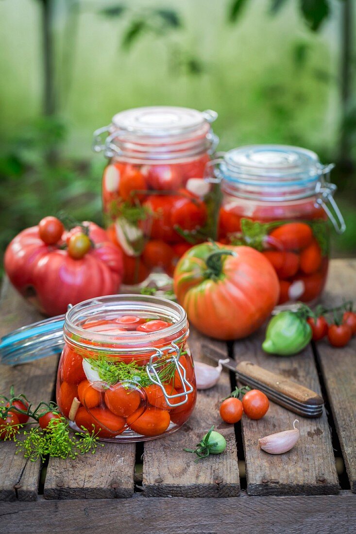 Preserved and fresh tomatoes with ingredients on a wooden crate in the garden