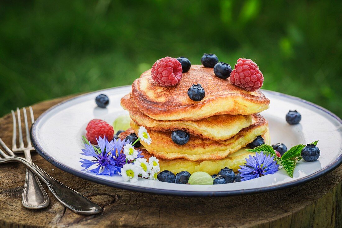 A stack of pancakes with fresh berries and maple syrup