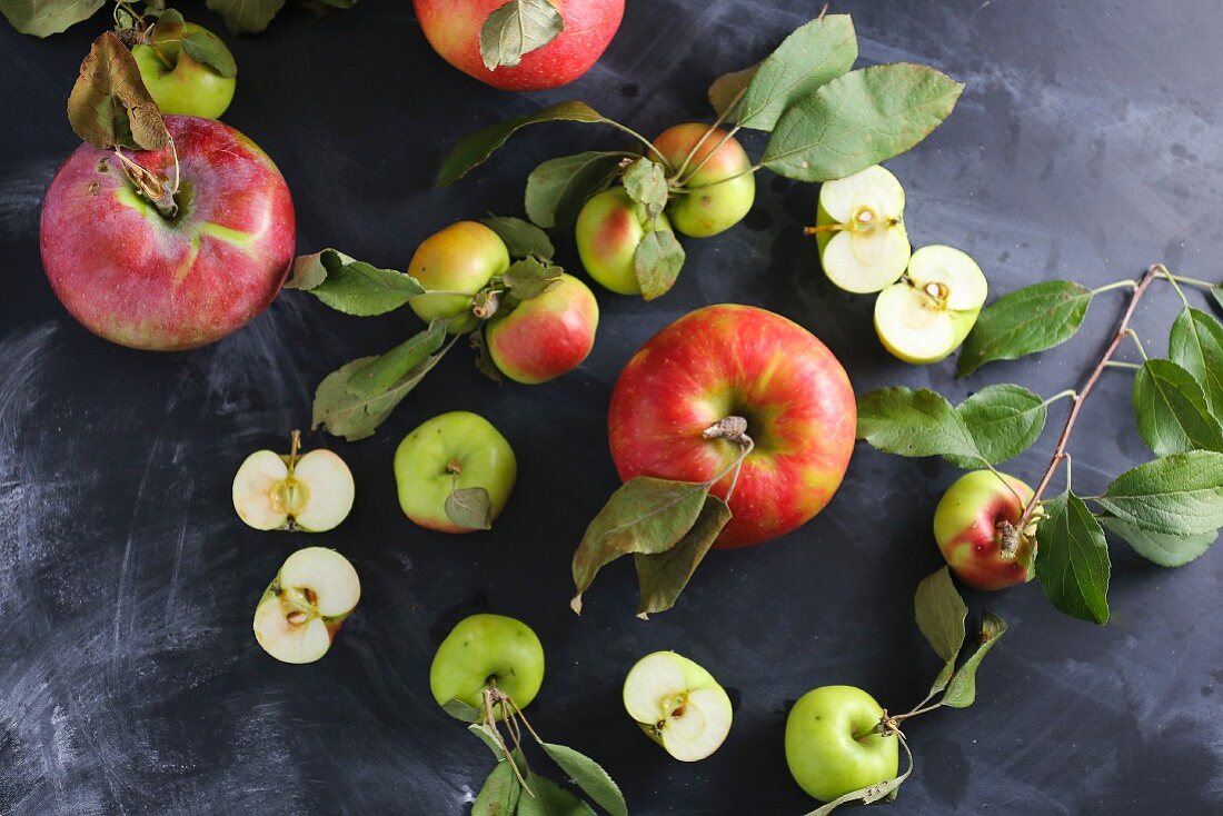 Assorted apples with leaves on a slate platter