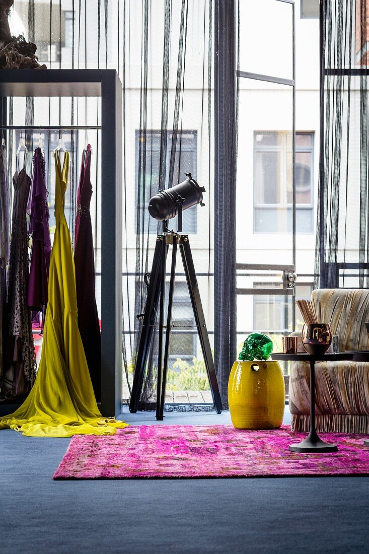 Feminine industrial style: colourful clothes on rail in front of industrial windows