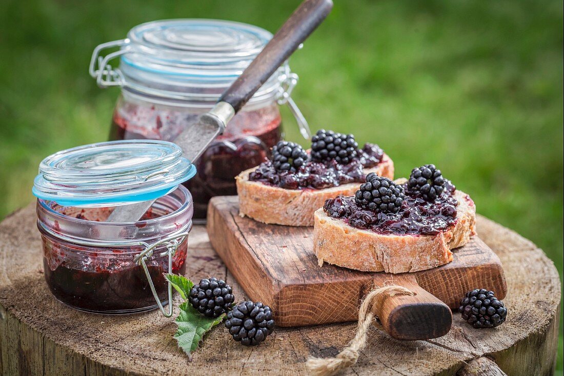 Bread topped with blackberry jam on a wooden board in the garden