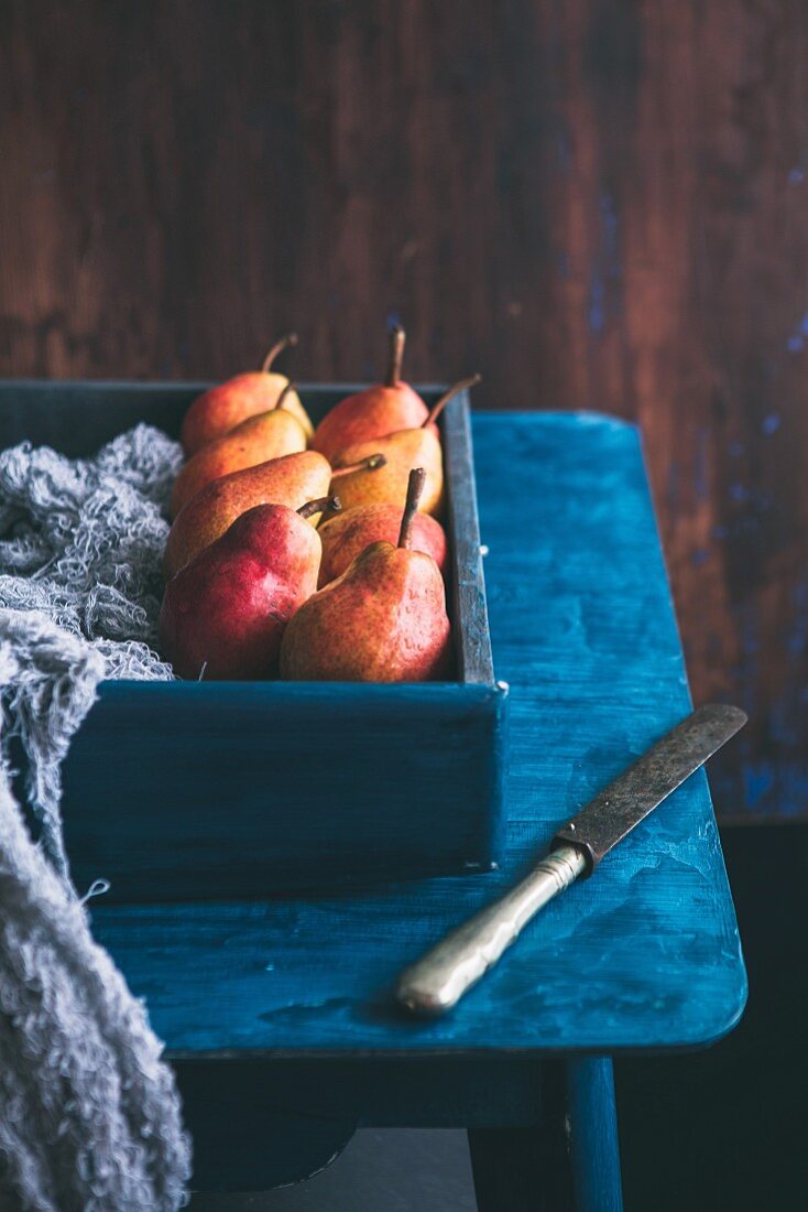 Birnen in Holzkiste auf blauem Tisch