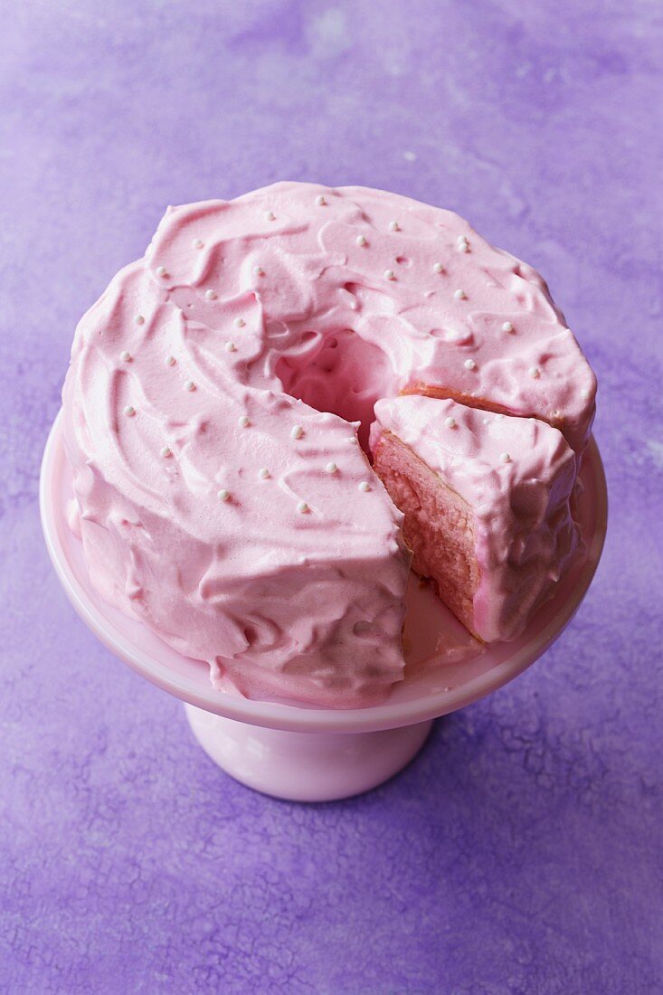 A sliced pink angel cake on a cake stand