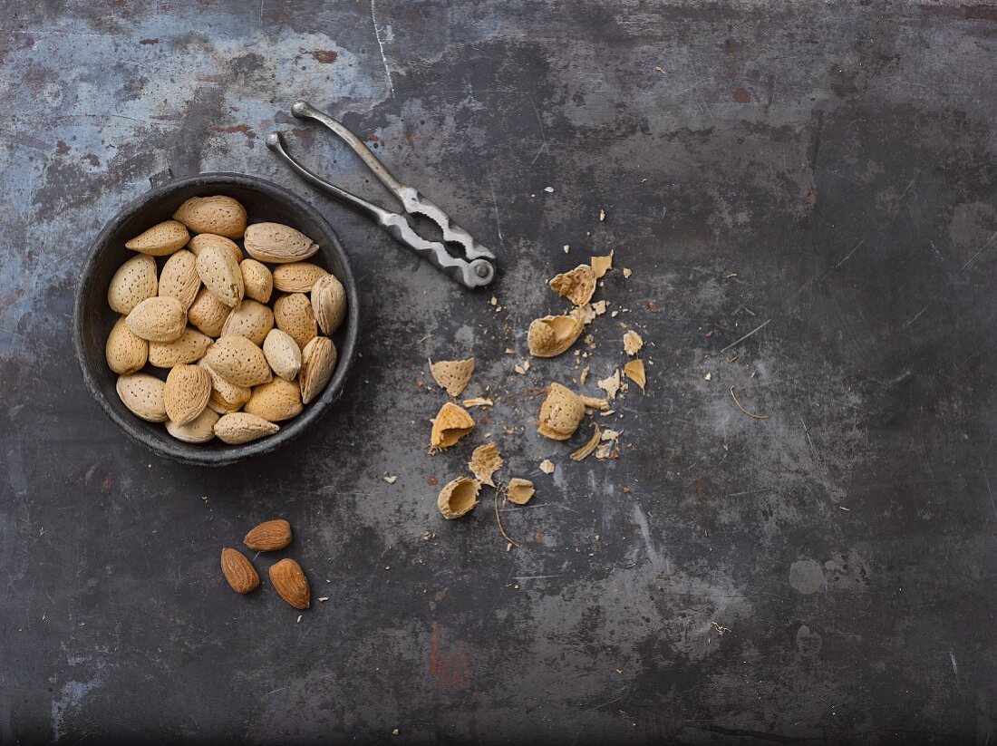 Whole almonds, a nutcracker, nutshells and almond seeds