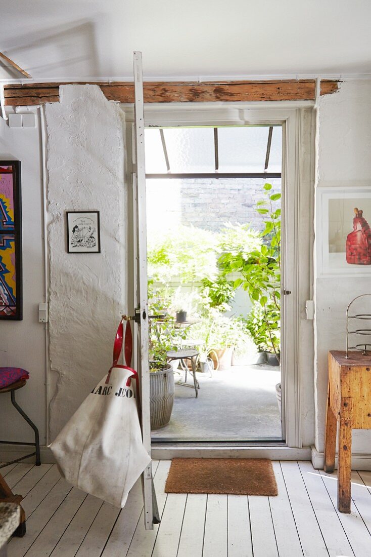 Open vintage back door with view of foliage plants on terrace