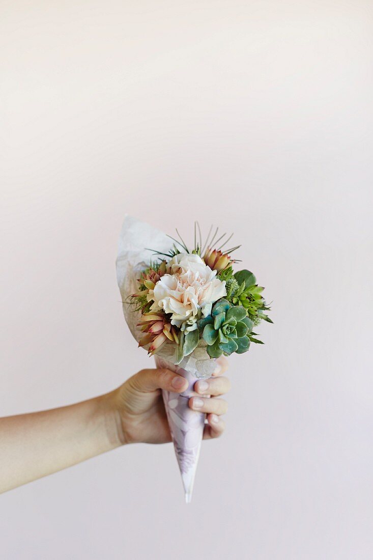 Delicate winter posy of flowers and succulents held in woman's hand