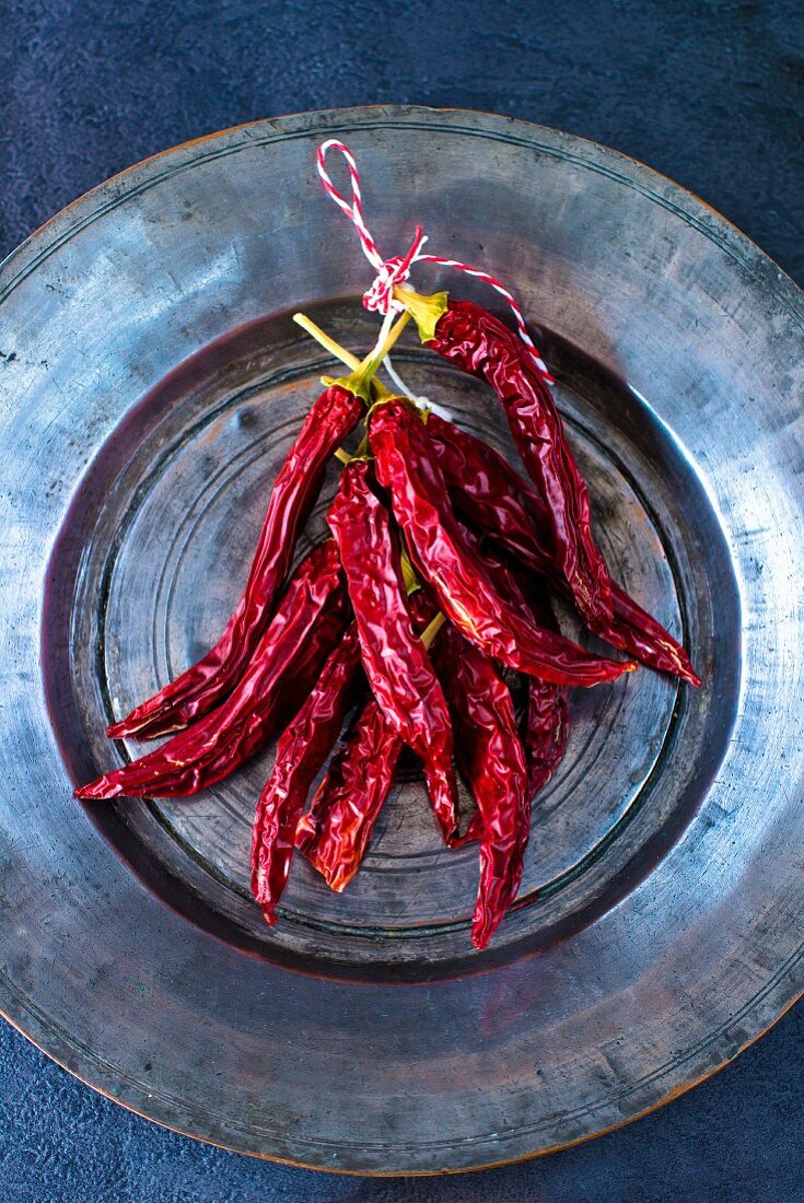 A bunch of dried red Indian chilli peppers on a Persian tin plate
