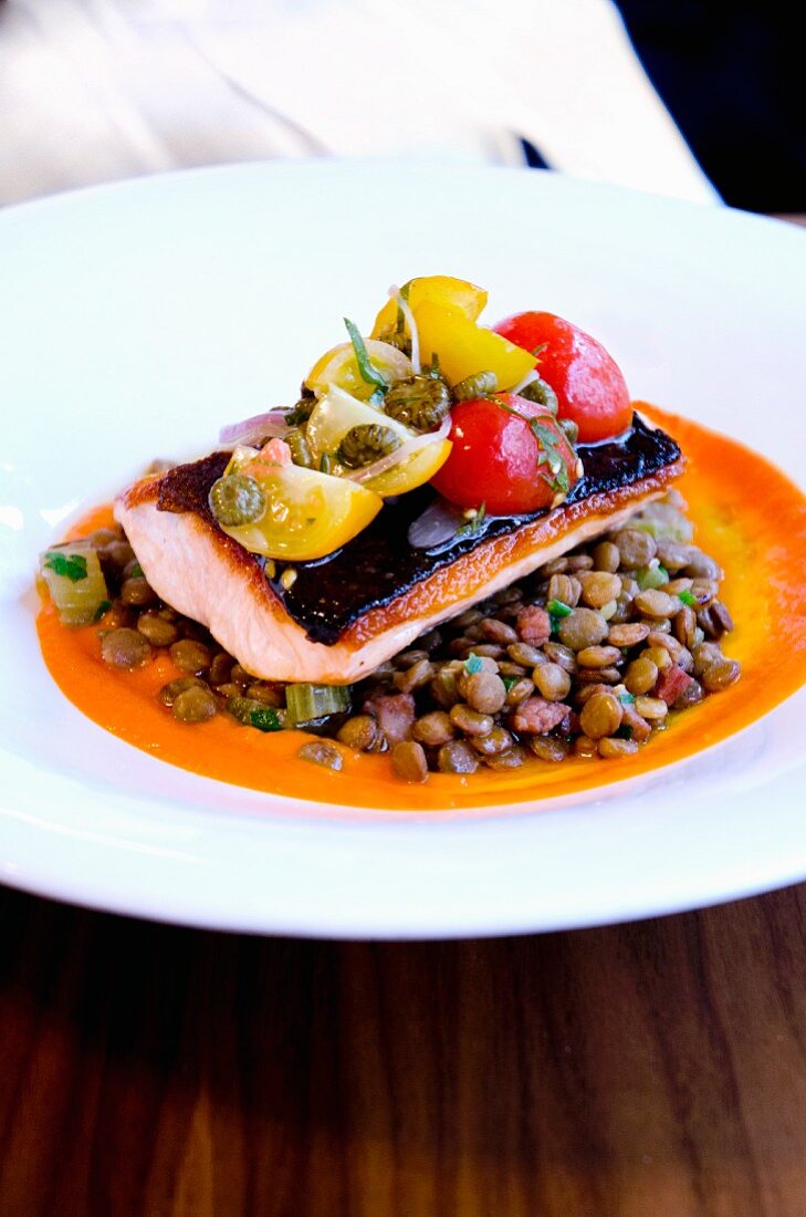 Pan-fried fillet of salmon on a bed of lentils with dried tomato jus and cherry tomato salsa