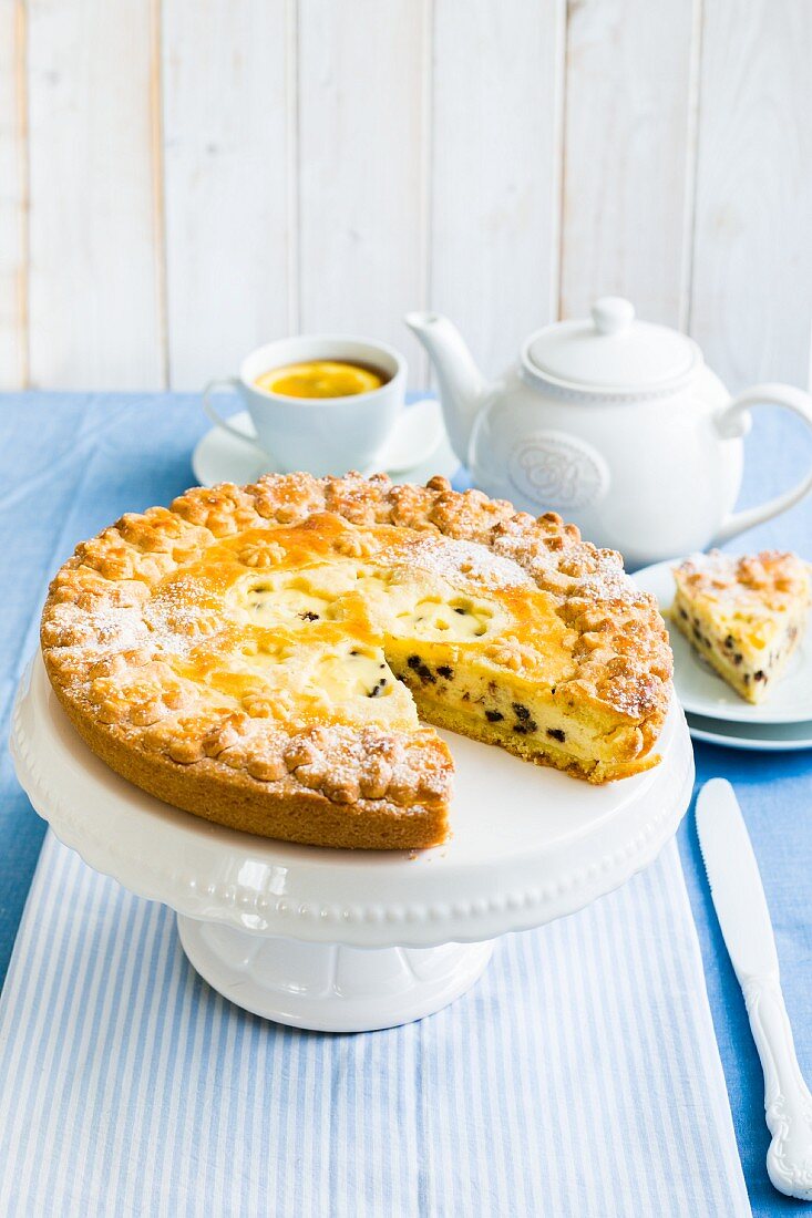 Greek ricotta crostata with chocolate chips on a cake stand