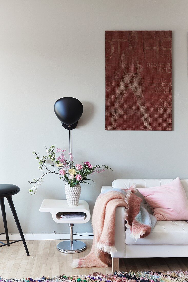 Vase of flowers on small retro side table in feminine interior