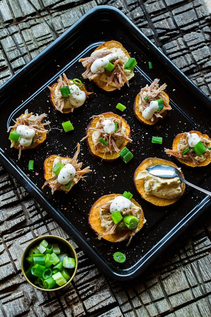 Sweet potato rounds with hummus, pulled pork, spring onions and sour cream