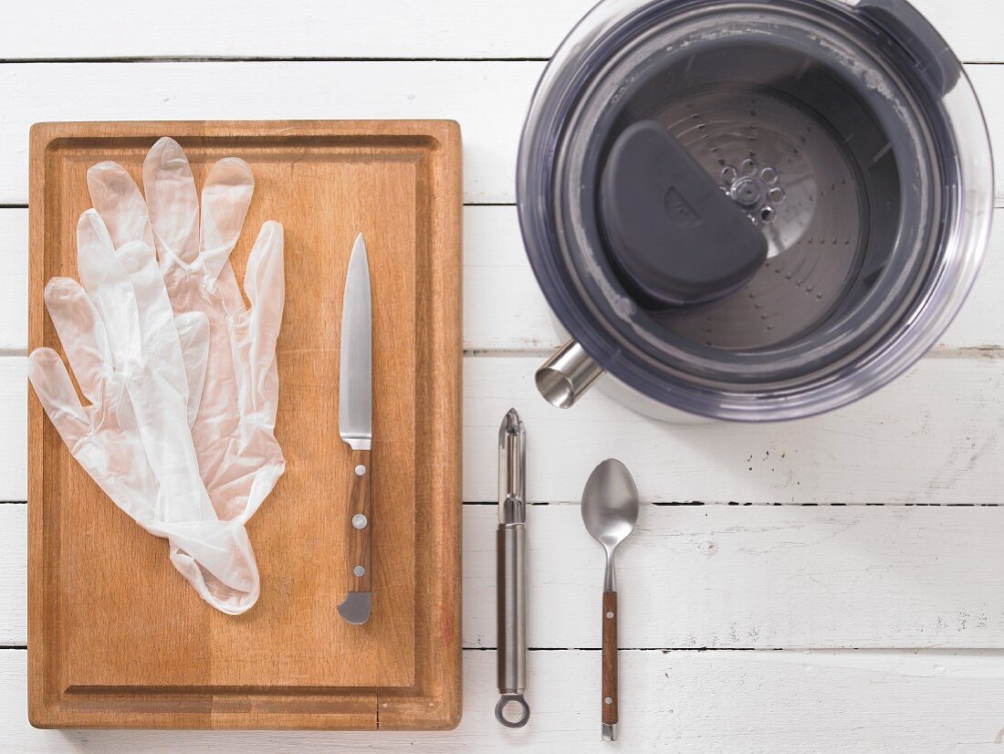 A juicer, disposable gloves, a knife, a peeler and a spoon